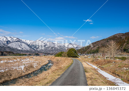 浅春の知内川と残雪の野坂山地　滋賀県高島市マキノ町 136845372