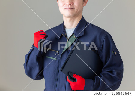 バインダーを持ってガッツポーズする作業服のミドル男性ビジネスマン 136845647
