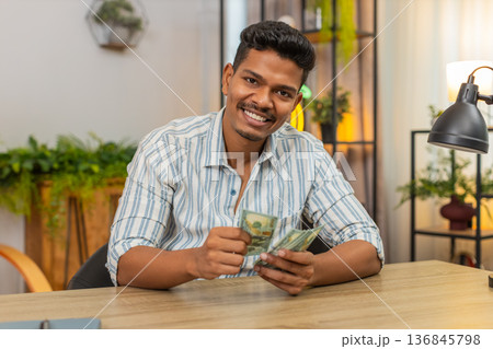 Indian man counts dollar cash after salary bonus plans invest smiles at earnings profit wealth joy 136845798