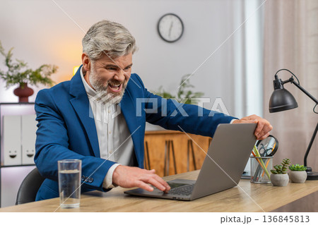 Middle-aged businessman fumes at laptop frozen error closes lid sighs disappointed frustration shows Middle-aged businessman fumes at laptop frozen error closes lid sighs disappointed frustration shows 136845813