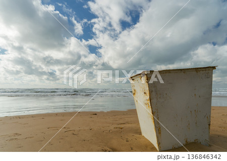 Trash container on a sandy beach. Post-storm trash and concern for the ecology of the sea and coast copy space for text 136846342