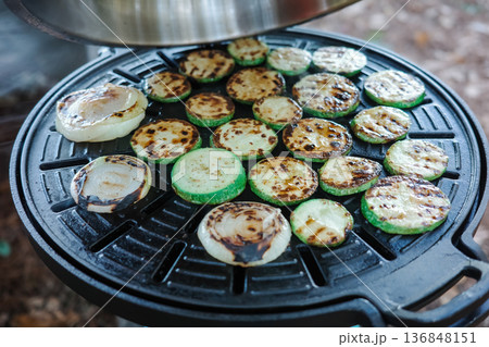 Top view of fresh grilled zucchini and onion slices with char marks on black non-stick BBQ grill plate, outdoor cooking and healthy eating concept 136848151