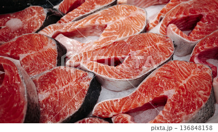 Fresh raw salmon steaks on display, bright orange fish meat with marble texture and skin, ready for cooking, seafood market background. Fresh raw salmon steaks on display, bright orange fish meat with marble texture and skin, ready for cooking, seafood market background. 136848158