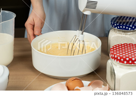 The process of beating eggs with sugar with a mixer, close-up, making the dough. 136848573