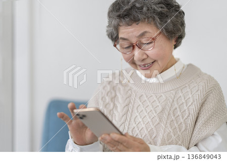スマートフォンを操作するメガネをかけたシニア女性 136849043
