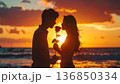 夕日の海でバラを持ち合うカップル 136850334