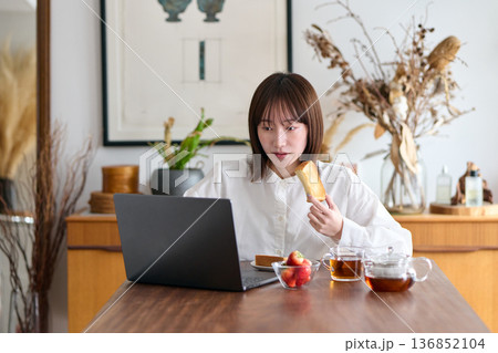 仕事をしながらパンを食べる女性 136852104