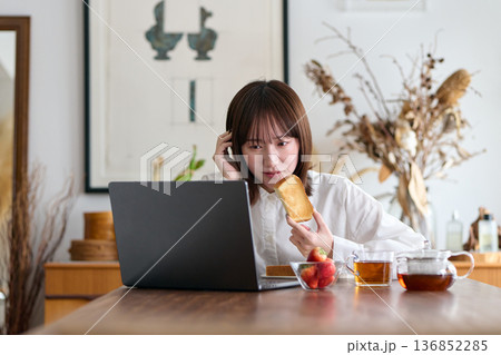 仕事をしながら朝食を食べる女性 仕事をしながら朝食を食べる女性 136852285