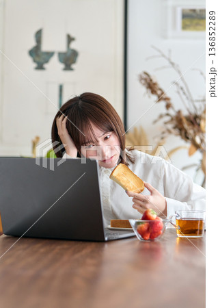 仕事をしながら朝食を食べる女性 仕事をしながら朝食を食べる女性 136852289