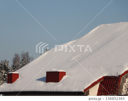 Snow-covered roof with red chimneys under a clear blue sky Snow-covered roof with red chimneys under a clear blue sky 136852365