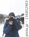 雪の街並みでカメラを構える女性　冬の旅スナップ 136852963