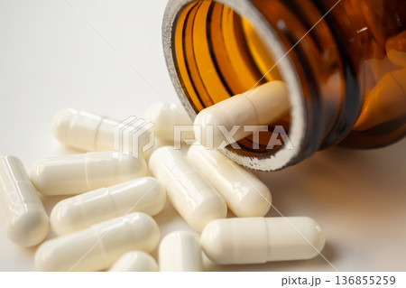 medicine pills capsule spilling out of bottle on white background 136855259