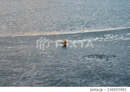 Volleyball ball on the river ice. The ball on the ice. A ball on the water 136855981
