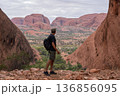 Hiker standing between red domes viewing vast landscape of Kata Tjuta, Australia 136856095