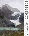 Hiker standing by Laguna Los Perros below massive glacier, Patagonia, Chile 136856103