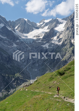 Hiker on Tour du Mont Blanc trail viewing glaciers in Val Ferret, Switzerland 136856105