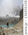 Hiker navigating rocky terrain below misty Torres del Paine, Patagonia 136856108