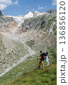 Hiker observing glacier and river valley on Tour du Mont Blanc, Switzerland 136856120