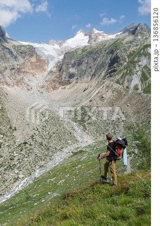 Hiker observing glacier and river valley on Tour du Mont Blanc, Switzerland Hiker observing glacier and river valley on Tour du Mont Blanc, Switzerland 136856120