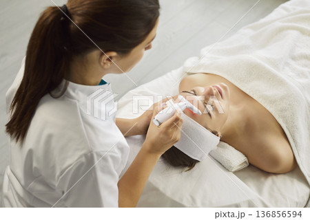 Young woman receiving ultrasound facial cleaning procedure lying on couch in beauty clinic. Young woman receiving ultrasound facial cleaning procedure lying on couch in beauty clinic. 136856594