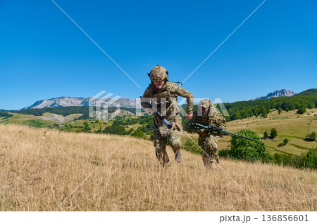 Two Soldiers in Camouflage Moving Uphill During Mountain Military Patrol and Sniper Training Exercise 136856601