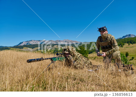 Military Sniper And Spotter In Camouflage Field Training With Drone Controller In Mountain Landscape Military Sniper And Spotter In Camouflage Field Training With Drone Controller In Mountain Landscape 136856613