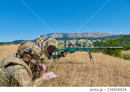 Military Sniper Team Training With Precision Rifle in Camouflage on Mountain Field During Daytime Exercise 136856626