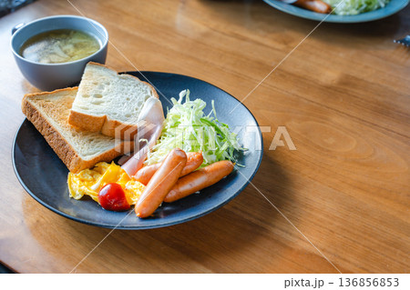 ソーセージと卵料理、千切りキャベツとトーストの洋朝食プレートを木のテーブルで撮影 136856853