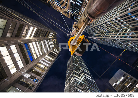 Night view looking up at illuminated skyscrapers with overhead transit wires and a traffic signal. Night view looking up at illuminated skyscrapers with overhead transit wires and a traffic signal. 136857609