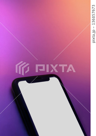 Close up of smartphone with white screen on pink purple neon surface Close up of smartphone with white screen on pink purple neon surface 136857673
