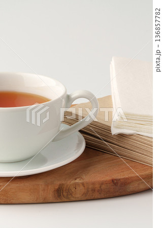 Hot tea in a white cup on a wooden board with napkins nearby in a simple setting 136857782