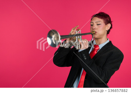 Musician playing trumpet against pink background 136857882