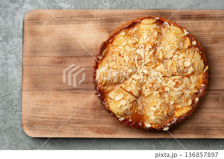 Pastry with sliced fruit and nuts on a wooden board in a kitchen setting Pastry with sliced fruit and nuts on a wooden board in a kitchen setting 136857897