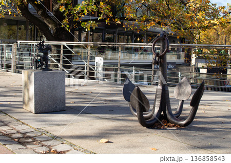 Sculptures of an anchor and a small figure in a riverside park setting Sculptures of an anchor and a small figure in a riverside park setting 136858543
