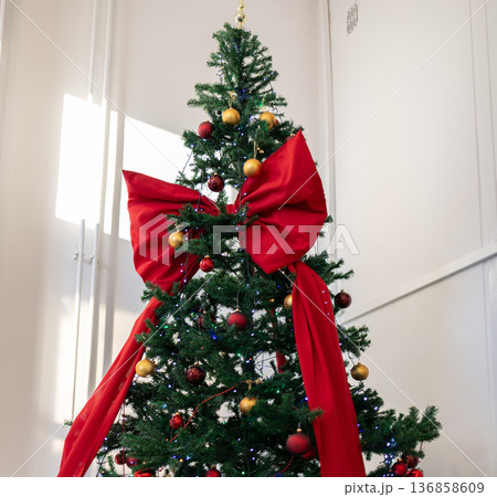 Christmas tree decorated with red bow and ornaments in bright room 136858609