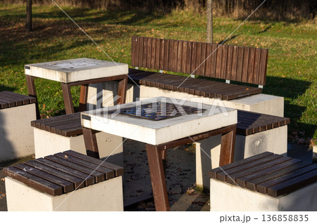 Outdoor seating area with wooden benches and a table in a park setting Outdoor seating area with wooden benches and a table in a park setting 136858835