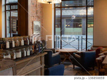 Cozy coffee shop scene with comfortable seating and large windows Cozy coffee shop scene with comfortable seating and large windows 136858859