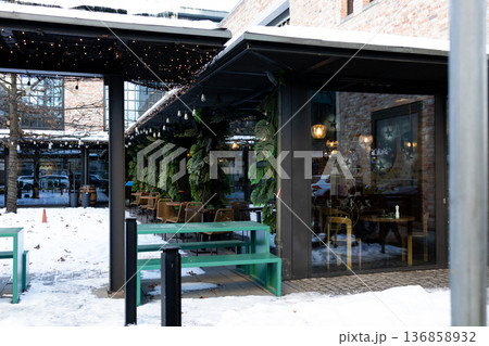 Cafe with outdoor seating in winter showing snow and greenery near city center 136858932