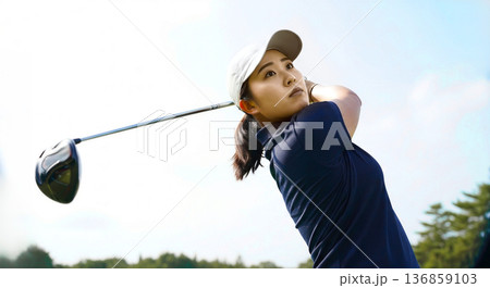 青空を背景にスイングする女性ゴルファー 真剣 集中 休日 スポーツ 健康 背景 136859103