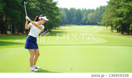 ゴルフ場でスイングする笑顔の若い女性 ゴルフ女子 スポーツ レジャー 趣味 初心者 ライフスタイル 136859108