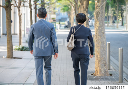 オフィス街を歩く男女の背後姿 オフィス街を歩く男女の背後姿 136859115