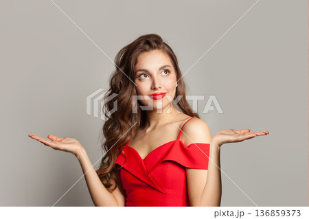 Healthy model woman holding empty open palm hand and looking up on white background 136859373