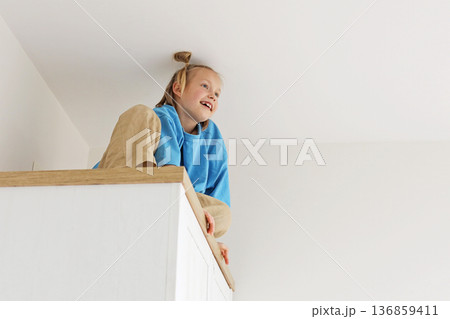 Child young girl climbing on a high cabinet having fun 136859411