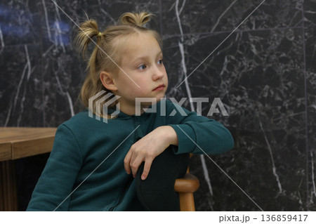 Cute blond child girl sitting in lounge. Young girl 6 years old portrait Cute blond child girl sitting in lounge. Young girl 6 years old portrait 136859417