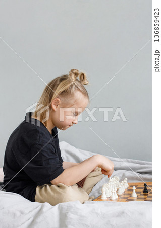 Smart little child girl playing chess while spending leisure time at home Smart little child girl playing chess while spending leisure time at home 136859423