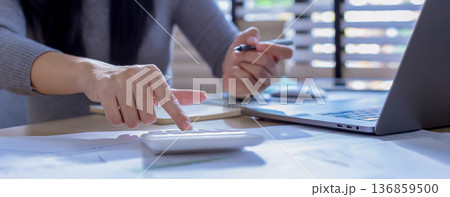 Business woman or accountant working on calculator to calculate business data in modern office.  136859500