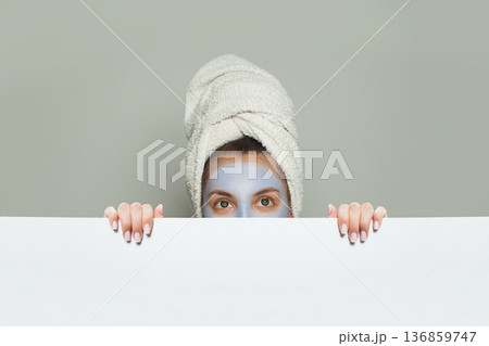 Attractive woman in blue cosmetic mask holding white empty banner background Attractive woman in blue cosmetic mask holding white empty banner background 136859747