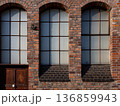 An old brick building with large arched windows and a wooden door 136859943