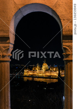 Budapest Parliament building illuminated at night. The architectural details are highlighted by warm lights. A clear sky enhances the scene. 136859949