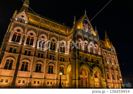 Budapest Parliament building illuminated at night. The architectural details are highlighted by warm lights. A clear sky enhances the scene. 136859954